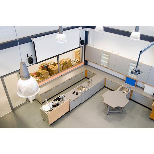 Ylhäältä kuvattu näkymä Länsikadun koulun opetustilasta, jossa on modernit kalusteet, kuten kaapit, tiskialtaat ja erikoismuotoiltu pöytä monipuolista opetusta varten.