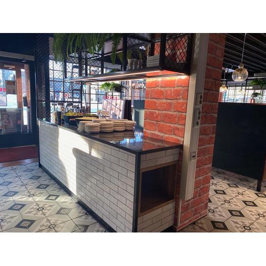 Rosso Joensuun moderni salaattip&ouml;yt&auml;, jossa tiilisein&auml;, valkoinen laattapinta ja metalliverkkoelementit yhdistyv&auml;t toiminnalliseen ja tyylikk&auml;&auml;seen sisustukseen.