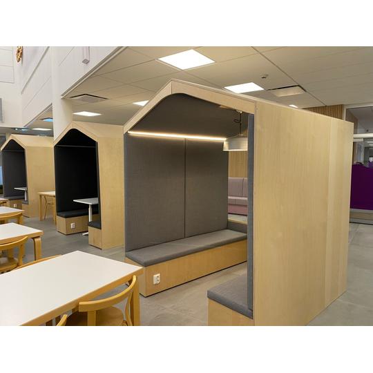 Puinen opiskelukoppi, jossa on pehme&auml;t istuimet ja valaistus.