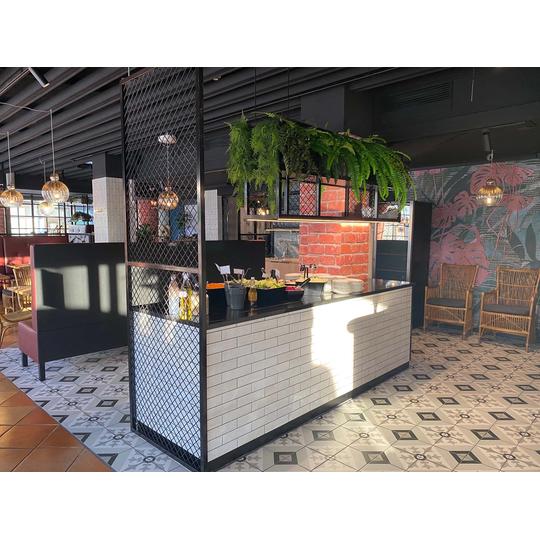 Rosso Joensuun salaattip&ouml;yt&auml;, jossa yhdistyv&auml;t moderni laattapinta, metalliverkkoelementit ja vehre&auml;t viherkasvit osana ravintolan trendik&auml;st&auml; sisustusta.