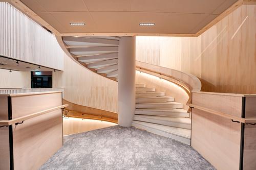 Moderni ja tyylikäs portaikko, jossa yhdistyvät puupaneeliseinät ja pehmeä valaistus, korostavat tilan arkkitehtuuria ja viimeisteltyä designia. Kuva: PKO.