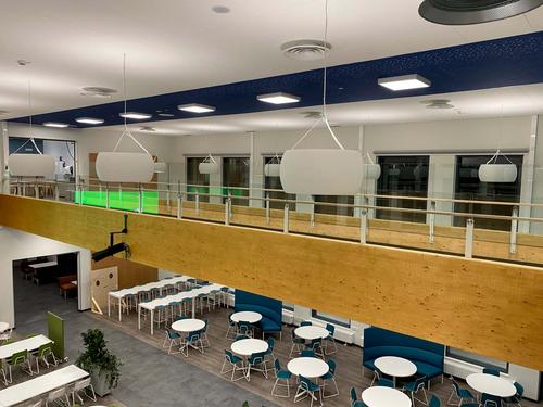 Kaksikerroksinen avotila, jossa yläkerrassa kulkee käytävä ja alakerrassa on oleskelutila. Puupintaiset kalusteet ja vihreät kasvit luovat lämpimän ja luonnollisen tunnelman.